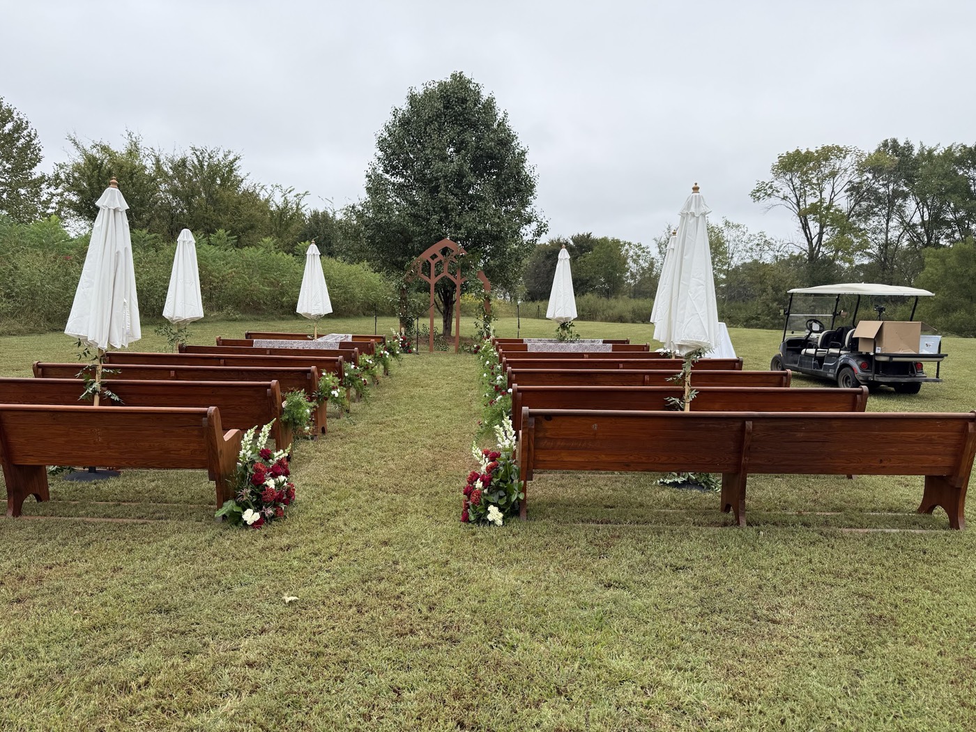 Wooden pews and umbrellas set for an outdoor ceremony