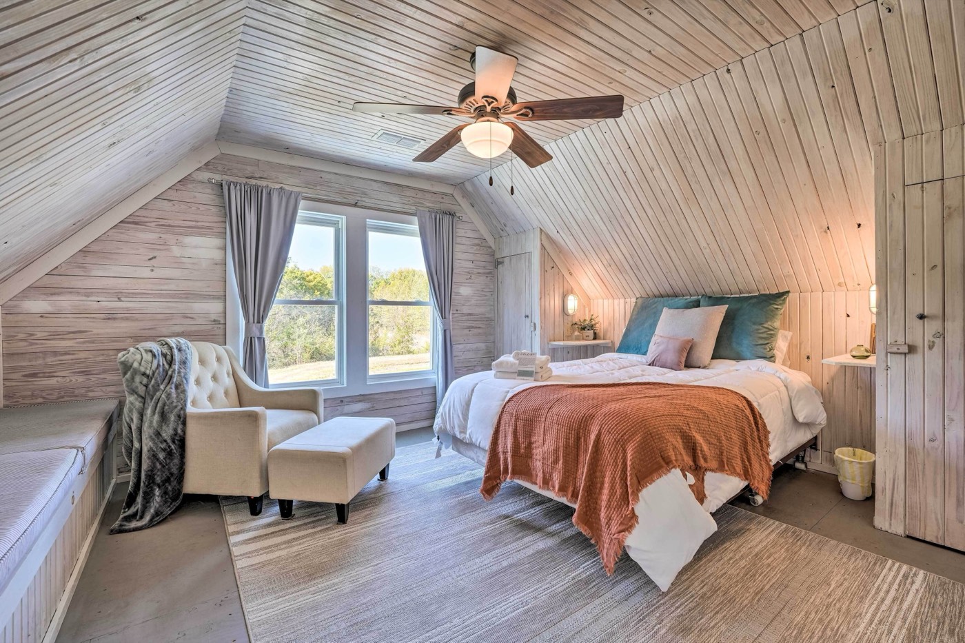 Loft bedroom with a queen bed, armchair and window