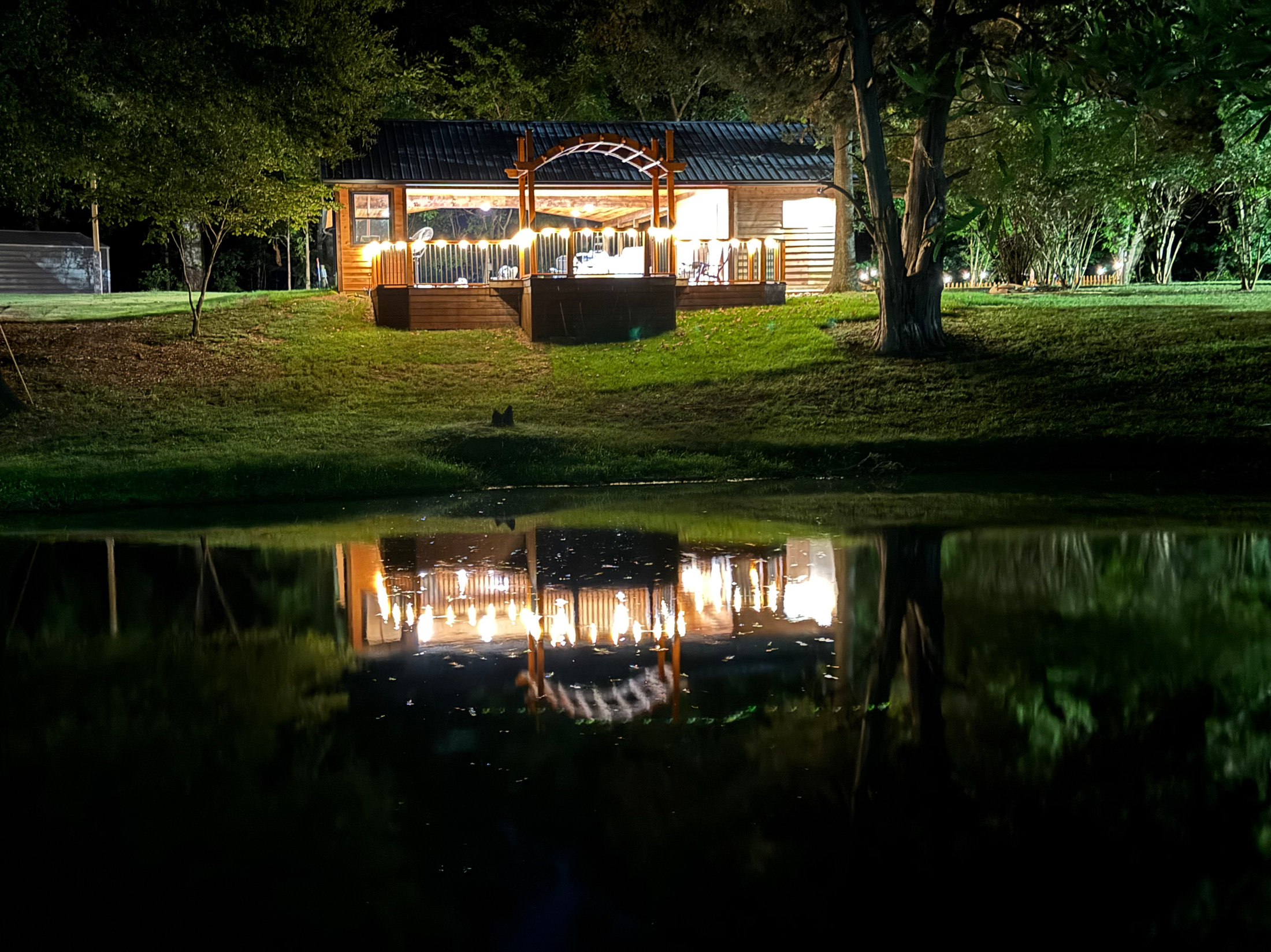 The Pavilion glowing at night, reflected in the pond